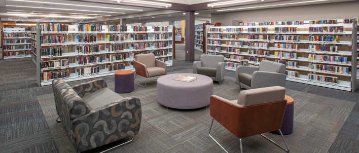 Photo of a library area with chairs and many bookshelves