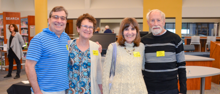 A group of four people, two men and two women, pose in front of the library main desk