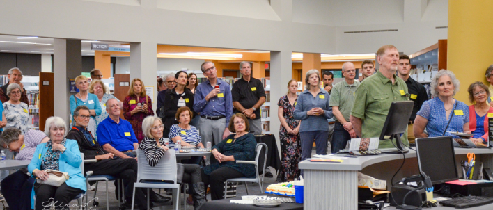 A large group of people listening to a speaker while standing in the library